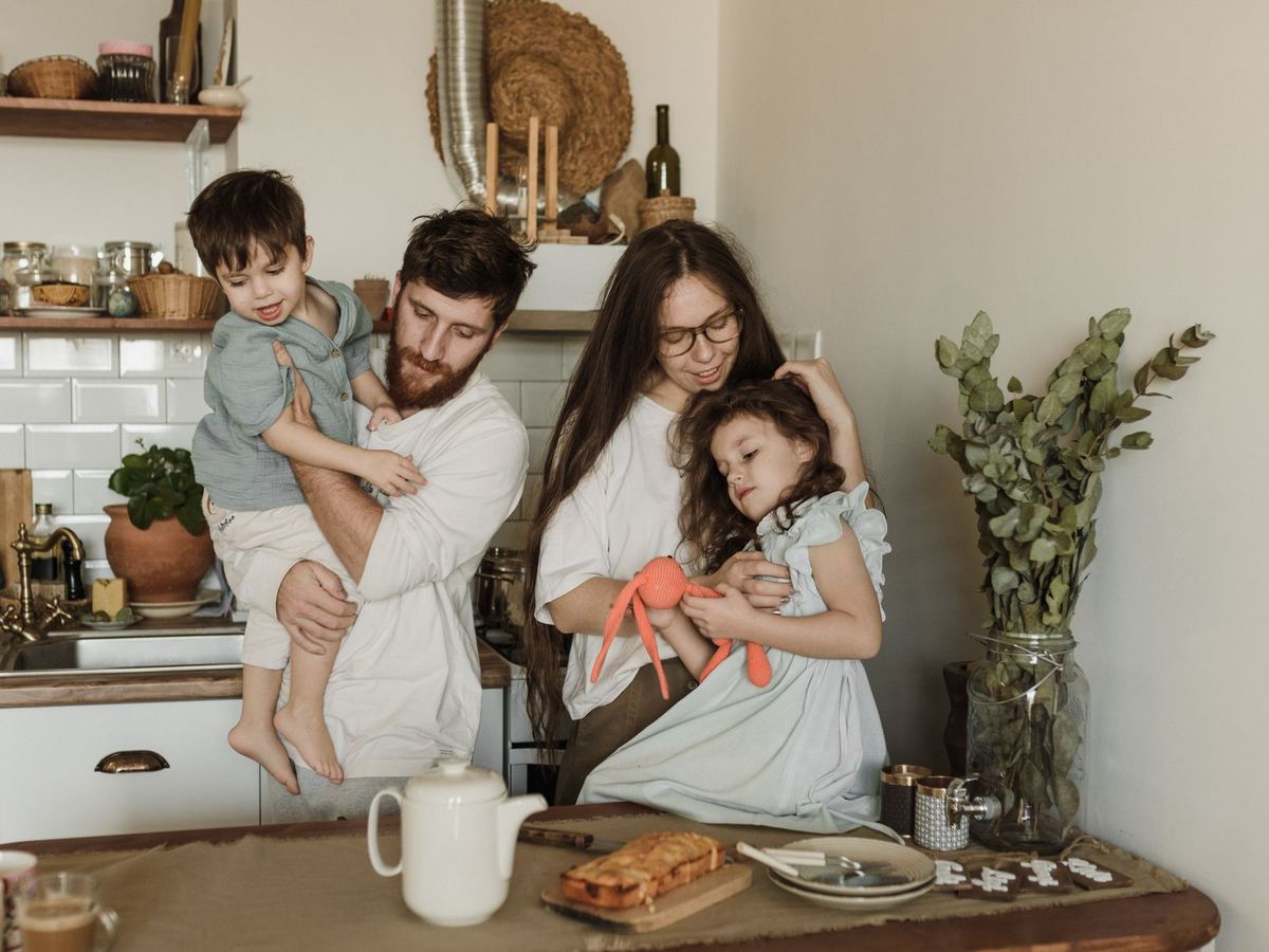 Young family of four sharing a happy moment in their kitchen