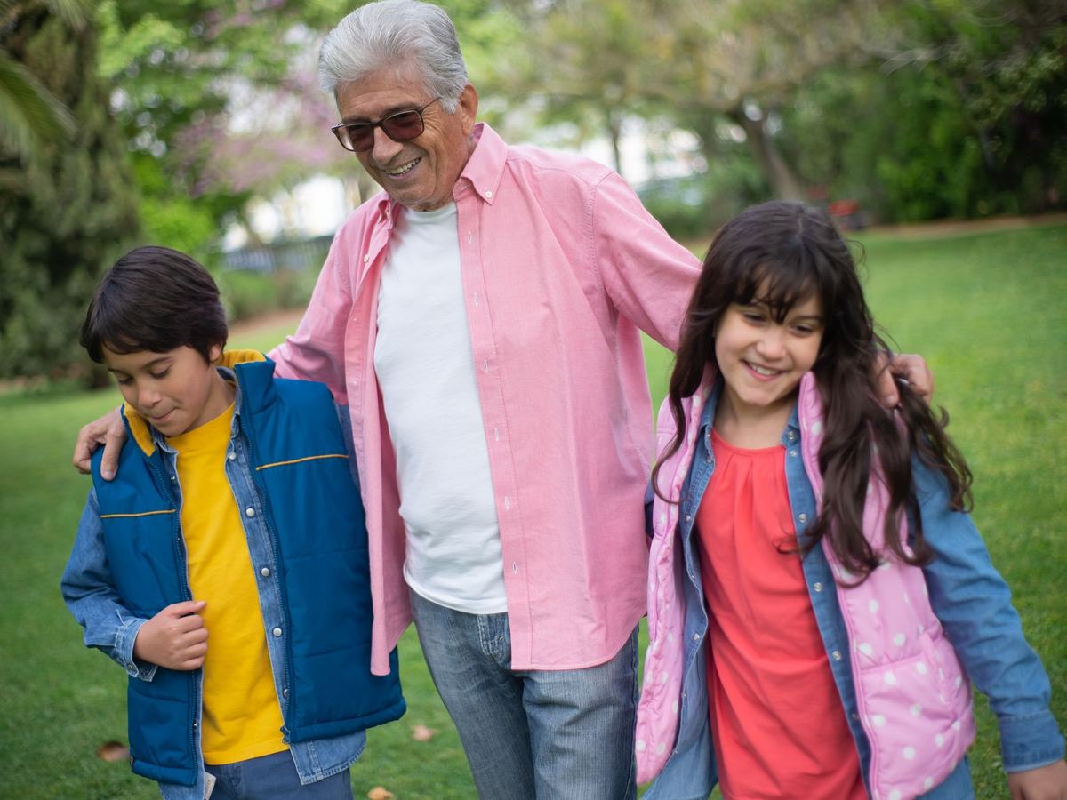 Grandfather walking outdoors with his two grandchildren